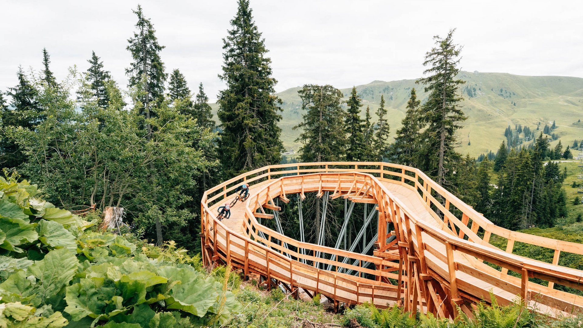 Zwei Mountainbiker auf einer hölzernen Spiralfahrbahn im Wald (© Patrick Wasshuber)